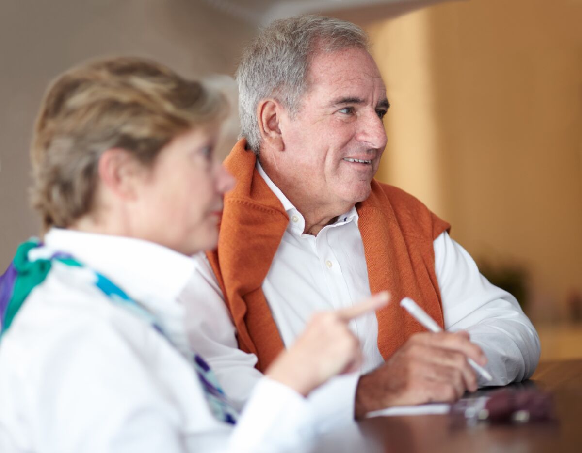 Smiling senior couple discussing Medicare plan options at a desk, highlighting the importance of expert guidance when reviewing Medicare plans in California.